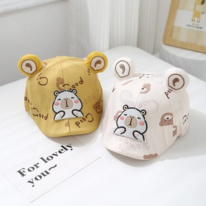 Detail view of yellow and cream baby caps with bear ears and cute cartoon patches