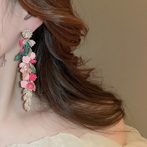 Detailed side view of floral tassel earrings with pink roses and green leaves on a model