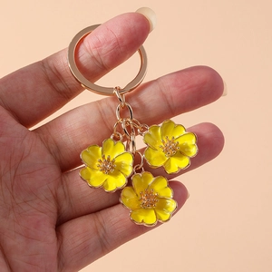 Close-up of golden keychain featuring three sweet yellow enamel peach blossom charms
