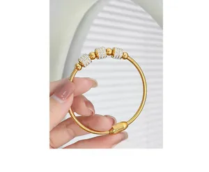 Macro detail of 18K gold-plated snake bone bracelet featuring crystal-encrusted beads