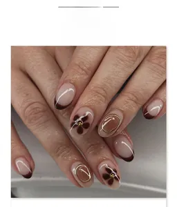 Close-up of nude short round nails with French tips and 3D gold embossed floral accents