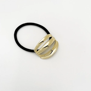Macro detail of elastic hair tie featuring a triple-layered gold hollow metal ornament