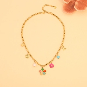 Detailed view of golden necklace with floral and butterfly pendants on beige background