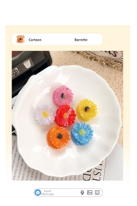 Colorful acetate daisy hair claws in pink, white, and yellow on a ceramic plate