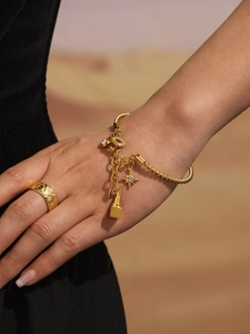 Detailaufnahme von goldenem Kordelarmband mit Sternanhängern und gehämmertem Siegelring