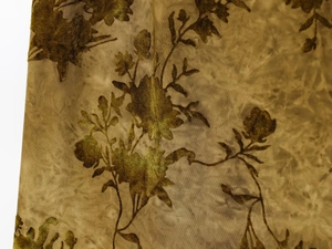 Vue macro détaillée du motif floral floqué bronze doré sur tissu en maille plissée