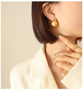 Detail of golden ball earrings and geometric rings with mirror finish on model