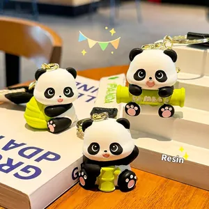 Cute resin panda keychains with green bamboo accents on a minimalist warm wooden surface