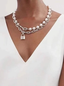 Detail of layered pearl and silver chain necklace with an engraved padlock pendant