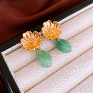 Macro detail of vintage gold flower earrings with green resin teardrop pendants