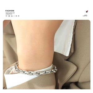 Detailed view of chunky silver chain bracelet with interlocking rectangular links on wrist