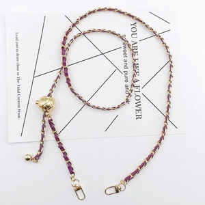Detail of a purple leather-woven gold metal chain strap with a decorative gold ball charm