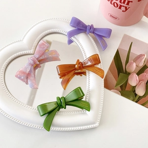 Set of four colorful acetate bow hair clips in purple, pink, orange and green colors
