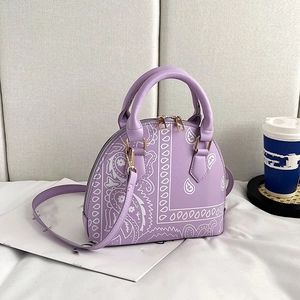 Detail of lavender shell bag with paisley patterns, golden hardware and shoulder strap
