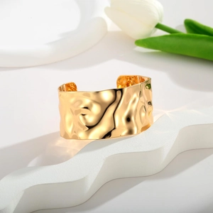 Detail view of a 18K gold-plated wide cuff bracelet with a modern hammered texture