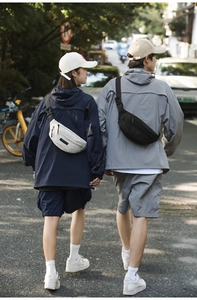 Outdoor street view of black and white waterproof crossbody chest bags on male and female models