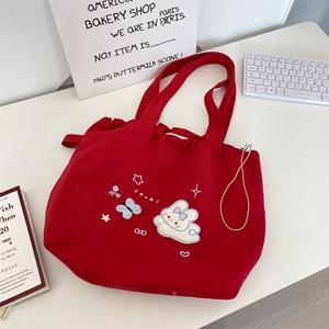 Detail shot of a red canvas drawstring tote featuring exquisite cartoon rabbit embroidery