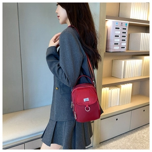 Detail of red water-resistant nylon crossbody bag with functional multi-zipper compartments