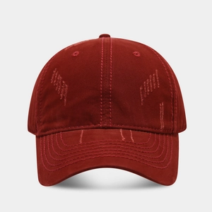 Close-up of distressed washed cotton texture and parallel stitching on wine red baseball cap