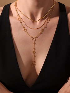 Detail of a layered gold necklace featuring a floral pendant with sparkling zircon accents