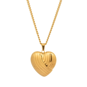 Détail du pendentif cœur doré avec rainures texturées et chaîne en spirale