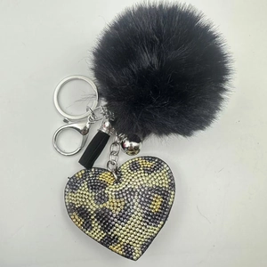 Detailed view of black faux fur pompom and leopard print rhinestone heart keychain