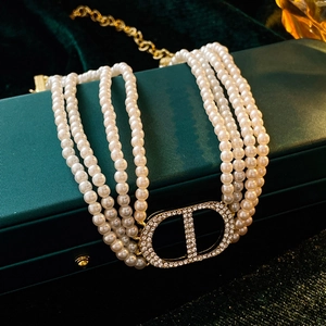 Detail of multi-strand pearl necklace featuring a sparkling diamond-set CD logo clasp