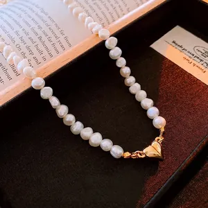 Baroque pearl necklace with gold heart magnetic clasp on vintage aesthetic background