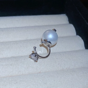 Macro shot of a minimalist silver ear cuff featuring a large pearl and a zircon stone