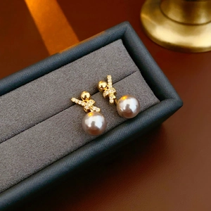 Detail of 18k gold plated zircon and grey pearl stud earrings in a jewelry box