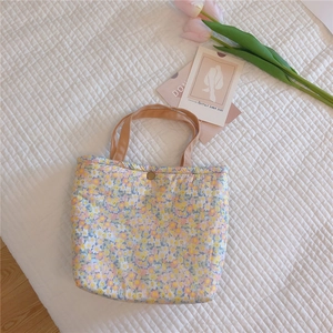Close-up of floral quilted tote bag with metal snap button and fabric handles