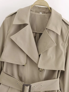 Detailed close-up of khaki short trench coat featuring classic lapels and adjustable waist belt