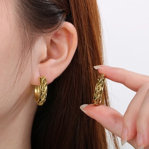 Macro shot of gold twisted rope C-shaped earrings showing premium metal texture and craft