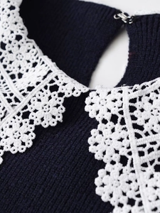 Close-up of crochet floral lace collar and metal hook closure on navy knit sweater