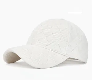 Detailed macro of white corduroy baseball cap showing quilted diamond texture pattern