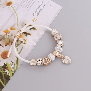 Detailed shot of a white braided leather bracelet with heart charms and crystal beads