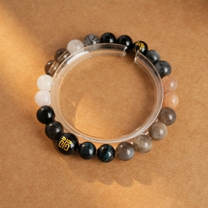 Detailed close-up of tiger eye and onyx beaded bracelet with golden totem charm