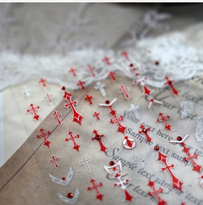 Detail of gothic 3D nail stickers featuring red and white cross designs with rhinestones