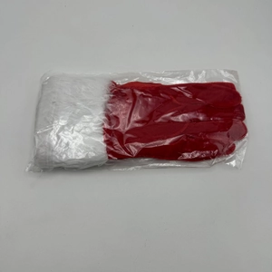 Macro shot of festive red Christmas gloves with white faux fur trim in plastic packaging