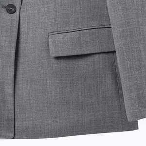 Close-up of grey wool-blend blazer featuring a single button and side pocket detail
