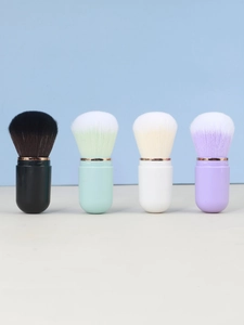 Detail of four colorful capsule-shaped retractable makeup brushes with gold ring accents