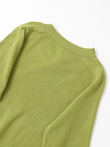 Close-up of fine knit texture and shoulder button detail on fruit green crewneck sweater