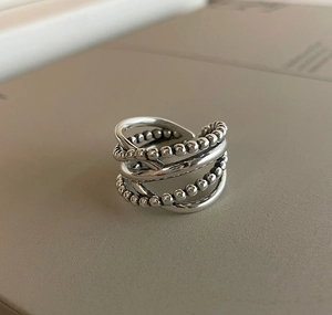 Macro detail of 925 sterling silver multilayer cross ring with beaded chain texture