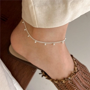 Close-up of minimalist S925 sterling silver beaded anklet on woman's ankle with woven shoes