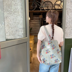 Detail of light green corduroy tote bag featuring Keep Smiling text and yellow smiley face