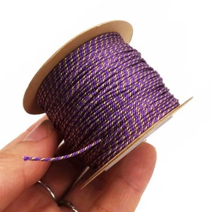 Detail of 1mm purple and gold metallic braided thread wound on a kraft paper spool