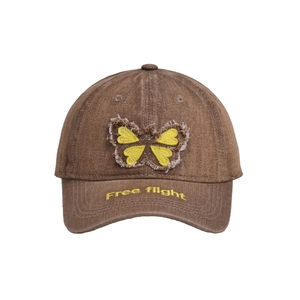 Close-up of butterfly embroidery and Free Flight text on a brown denim baseball cap