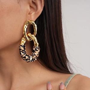 Close-up of model wearing gold chain earrings with leopard print fabric wrap detail