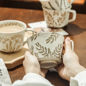 Hand-painted ceramic coffee mug with rustic floral patterns and matte beige finish