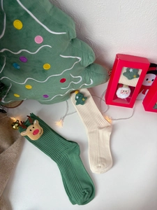 Close-up of Christmas socks with plush reindeer and tree figures in a festive gift box
